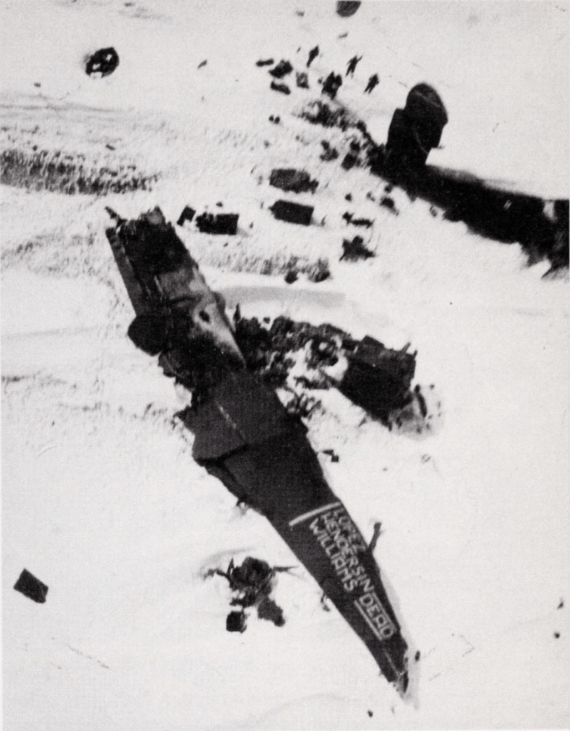 Phtograph showing the crash site on Antarctica with the surivors waiving and a message written on the wing of the plane