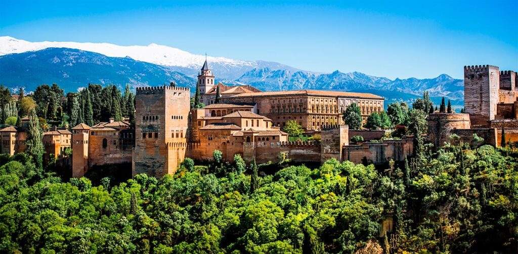 Alhambra Palace on a sunny day with snowy mountains in the background