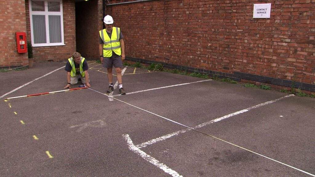 Two men look at a letter R spray painted onto the asphalt in a car park in Leicester, the site of Richard III's grave