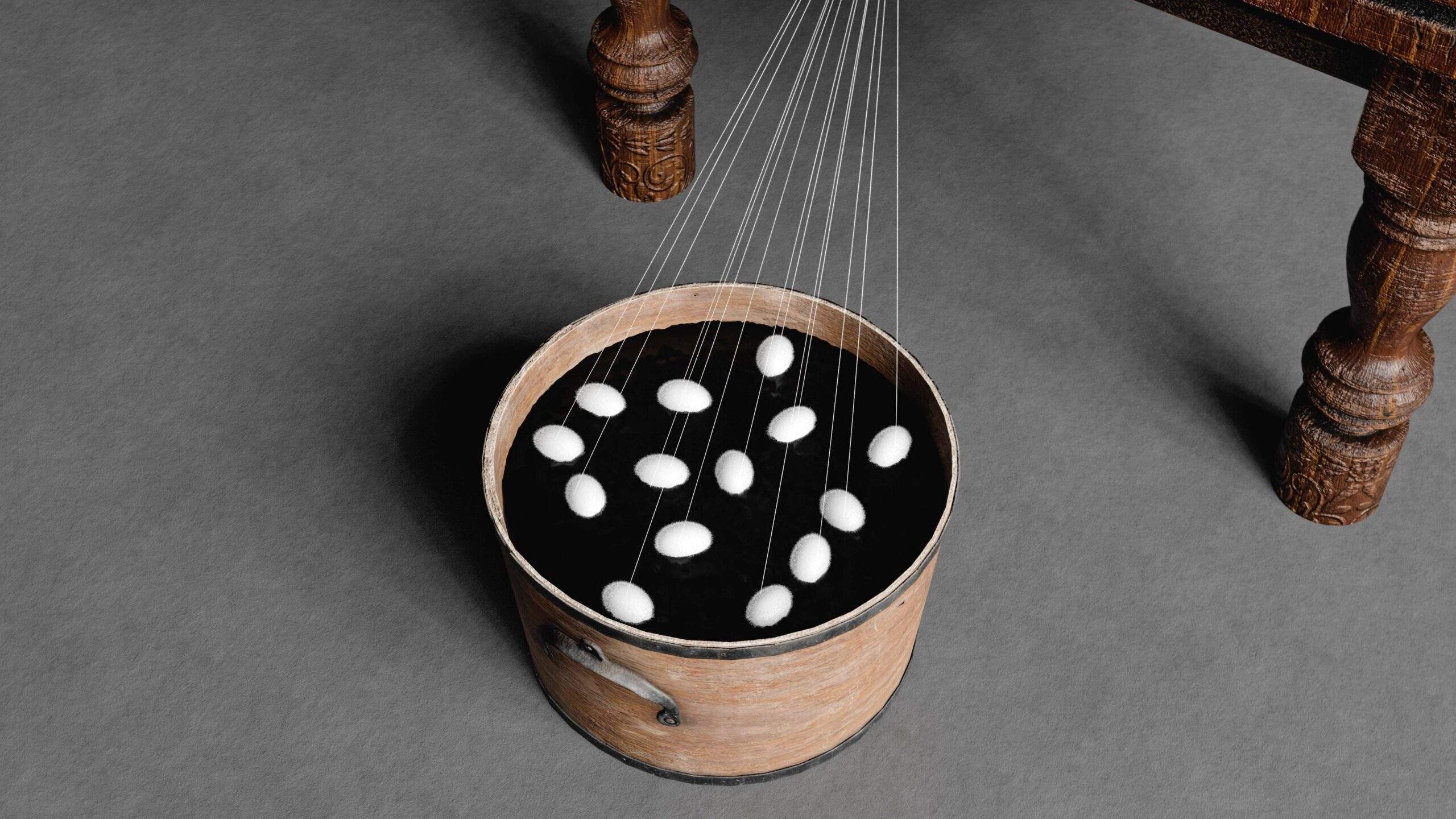 A bucket of silkworm cocoons as the threads are unraveled and reeled onto a silk reel